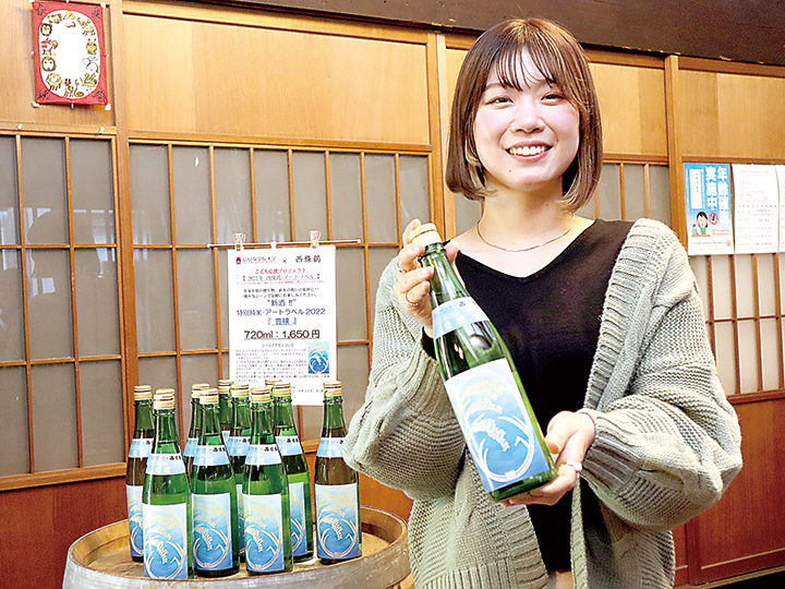 ラベルをデザインした「豊穣」を手にする三原さん