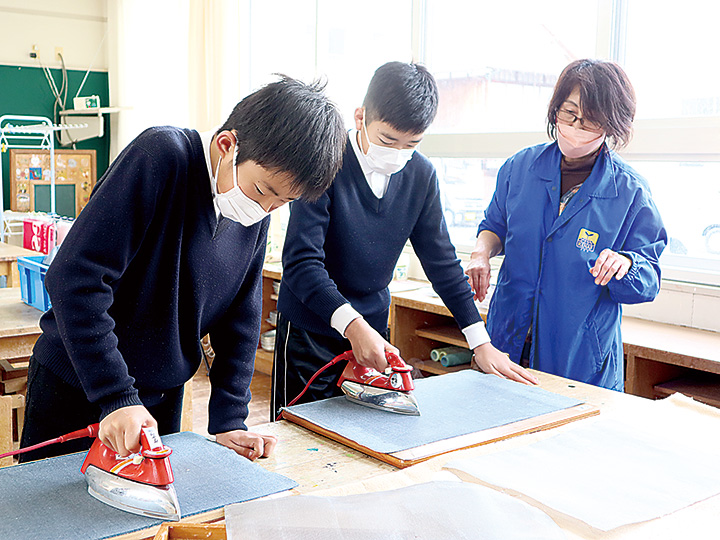 すいた紙にアイロンをかける児童と作業を見守る住田さん（右）（撮影・山北）