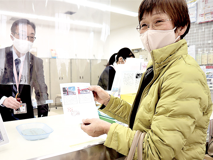 三上局長（左）に風景印を押印してもらい笑顔の来訪者（撮影・山北）