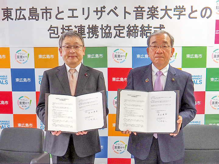 署名を終え、協定書を手にする高垣市長（右）と川野学長（撮影・原田）