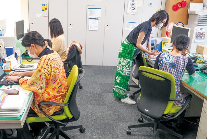 色鮮やかな民族衣装を着て仕事をする職員(撮影・原田)