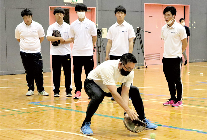ゴロの捕球体勢を学生に説明する野村さん(手前)(撮影・山北)