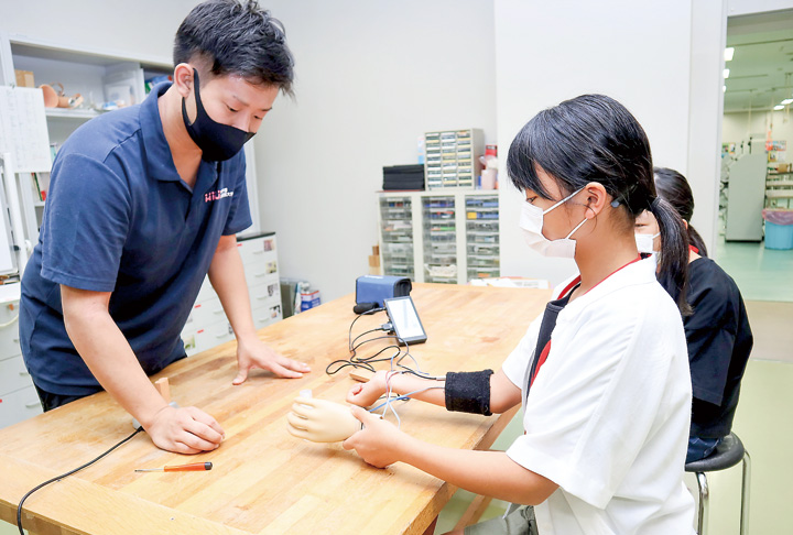 筋電義手を体験する参加者（撮影・山北）