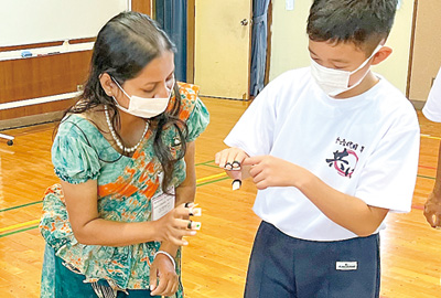 研修員（左）に琴の説明をする児童（撮影・林）