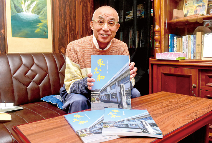 完成した記念誌を手にする仲島委員長(撮影・小林)