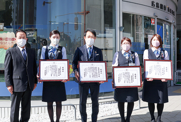 支店前での集合写真。左から中道署長、酒井副課長、藤井支店長、土井さん、井上さん（撮影・𦚰）