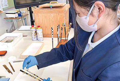 漆を塗った箸に銀粉を付ける児童（撮影・林）