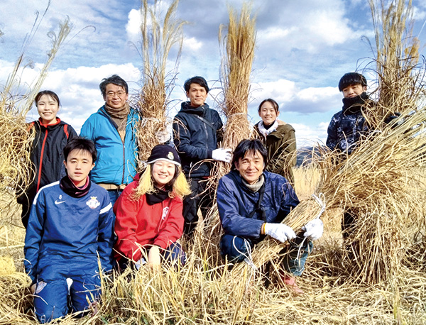 学生時代、地域の人たちとかや刈りに参加する（前列左から2人目が桜井さん）（提供写真）