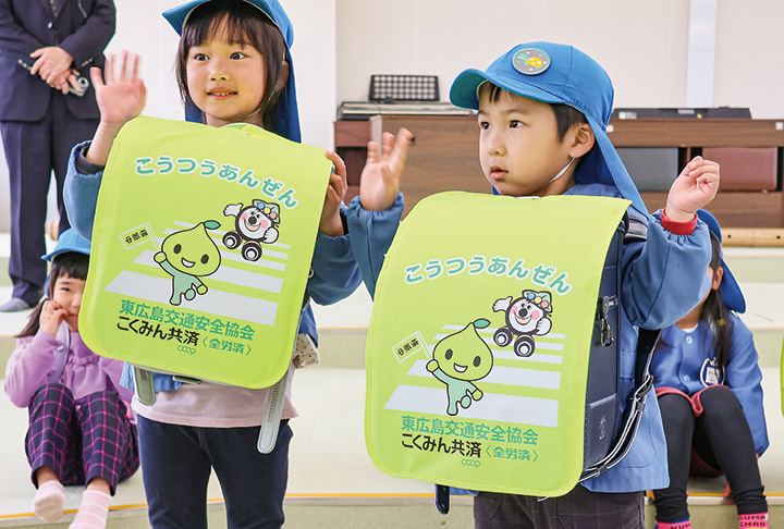 記念撮影用にカバーを付けたランドセルを体の前に持つ新1年生（撮影・𦚰）