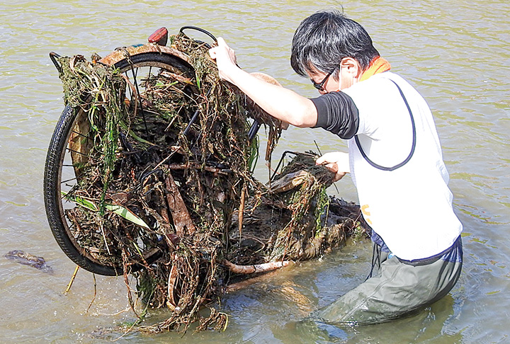 自転車を川から引き上げる参加者（撮影・𦚰）