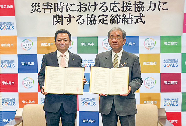 協定書を手に記念撮影する永岡社長（左）と高垣市長（撮影・久野）