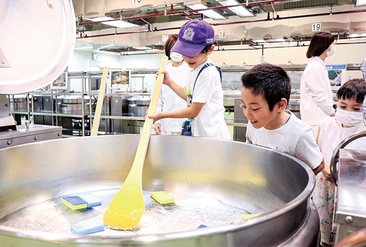 回転釜のかきまぜ体験をする子ども（撮影・山北）