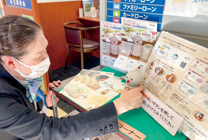 コミュニケーションロボット「BOCCO emo（ボッコ エモ）」の使い方を案内する広島銀行高屋支店行員（撮影・高藤）