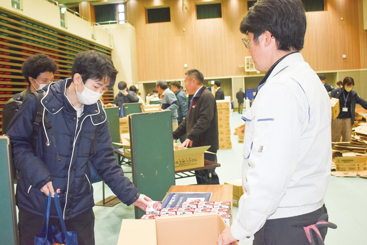 机に並べられた食料品を受け取る学生（左）（撮影・東原）