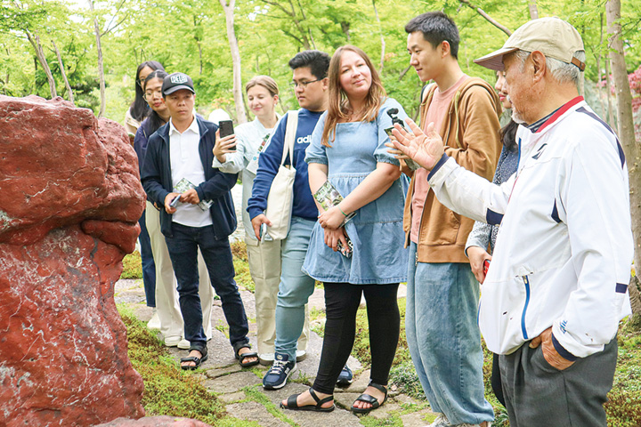 山名さん(右端)から庭石の説明を聞く留学生ら（撮影・山北）