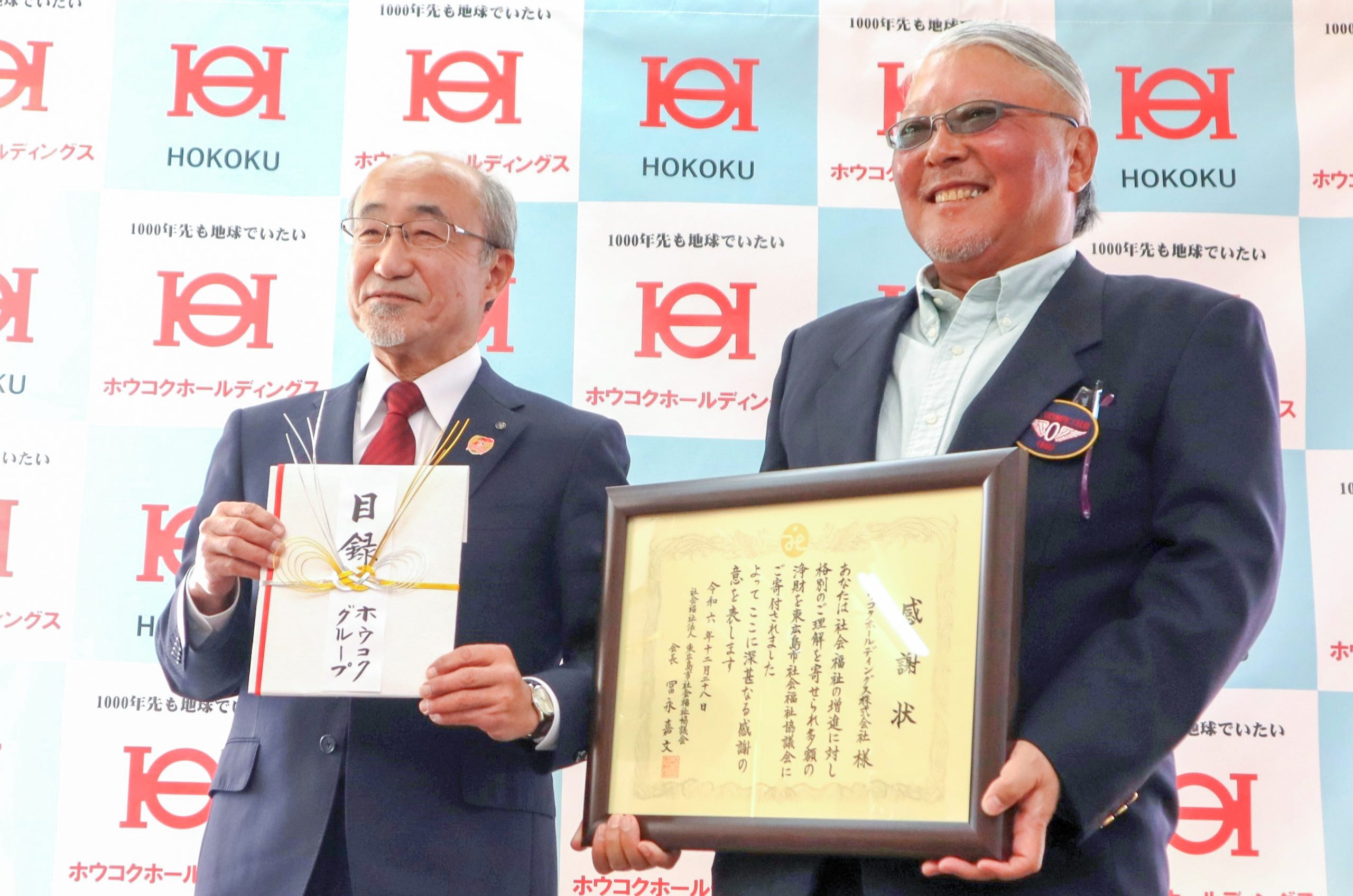 目録、感謝状を手に笑顔で記念撮影に臨む金谷社長（右）と冨永会長(撮影・山北)