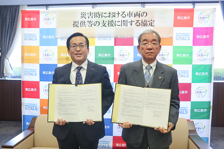 協定書を手に記念撮影する松本社長と髙垣市長