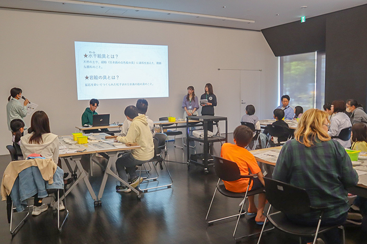 学芸員とHUMsスタッフからの説明を聞く参加者(撮影・山浦)