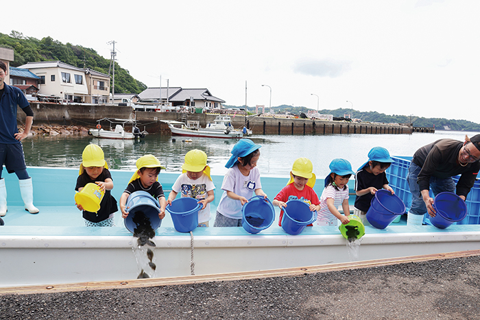 「大きくなってね~」と声をかけながらヒラメの稚魚を放流する園児ら(撮影・𦚰)