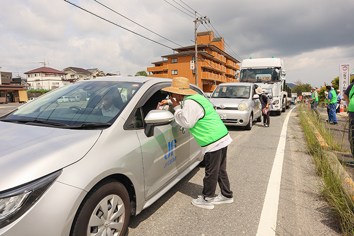 停車した車のドライバーに啓発チラシを手渡し、安全運転を呼び掛ける地域住民(撮影・山北)