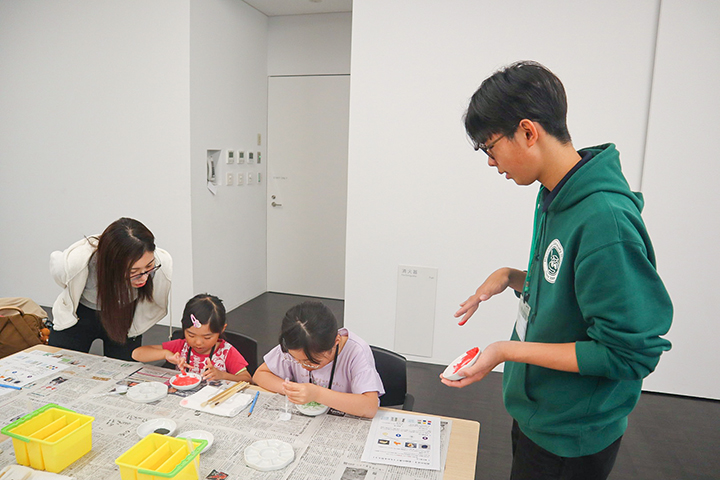 学生スタッフに説明を受けながら、水干絵の具を作る参加者ら(撮影・山浦)