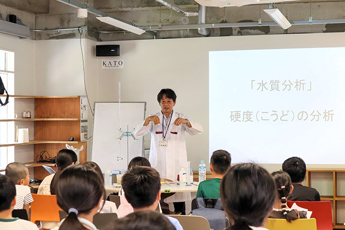 水質の分析実験をして子どもらに分かりやすく説明する竹野教授