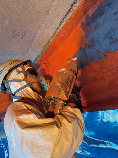 レーザーマシンで古い塗装を取り除くスタッフ