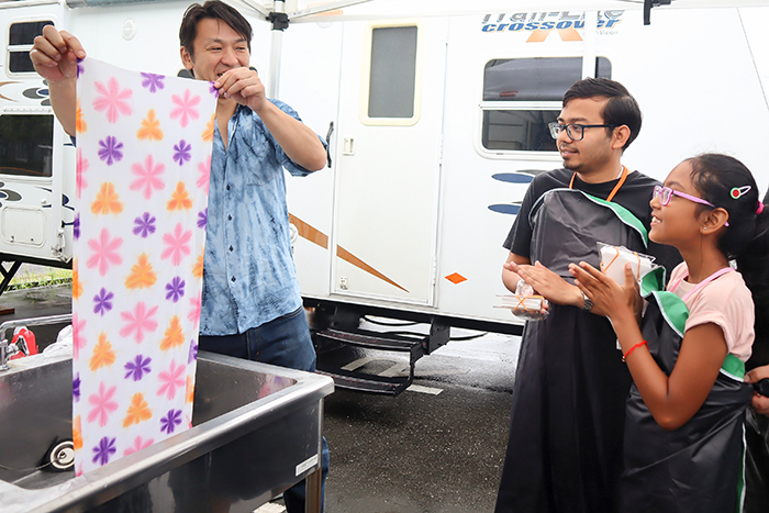 子どもが染色して山田講師(左）が水洗いするときれいな模様が現れ手をたたき喜ぶ子どもら