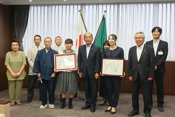 優勝を喜び記念記念撮影に応じる関係者ら