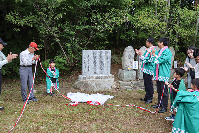 除幕された石碑を前に完成を喜ぶ参加者