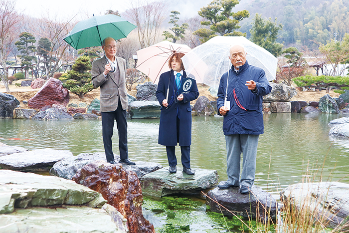 公式認定員と地質学の専門家に庭石の説明をする山名さん（右）